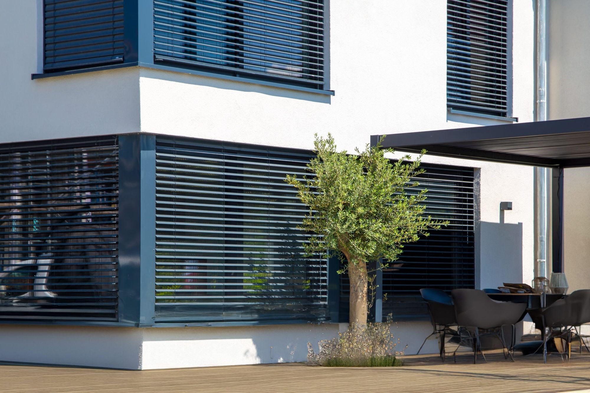 Moderne Fassade mit Außenjalousien und beschatteter Terrasse